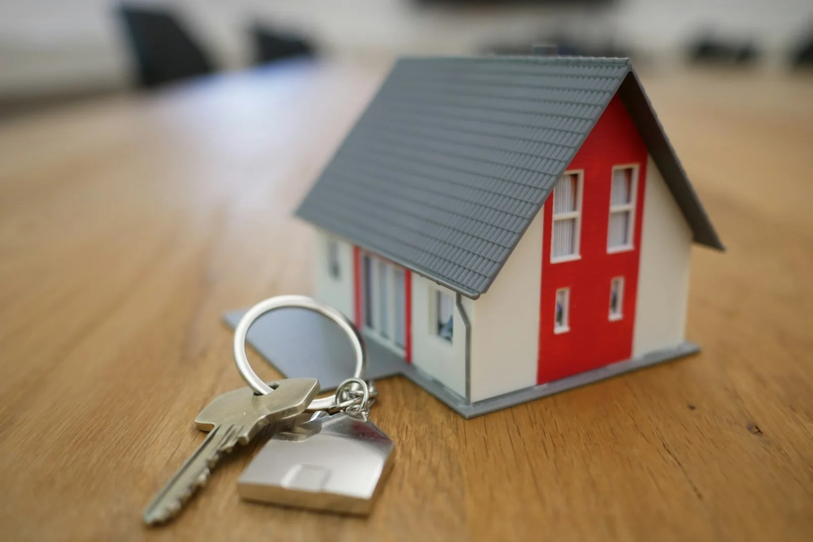 House keys on a wooden table beside homeownership paperwork