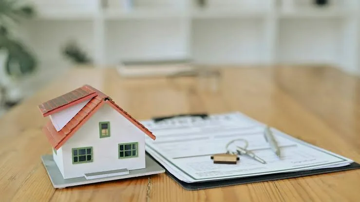 Signing mortgage documents with house keys and model home