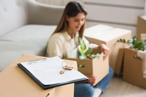 Rental agreement and keys on moving box with tenant unpacking