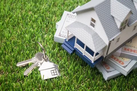 House model, keys, and cash on grass — rental property concept